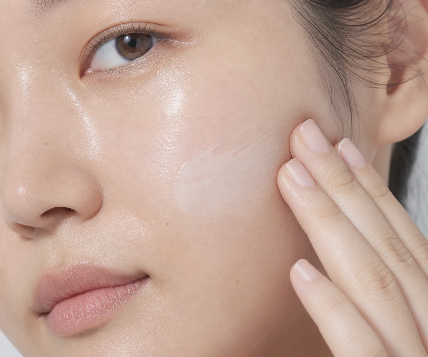 Fingertips pressing moisturizer into healthy, naturally textured skin